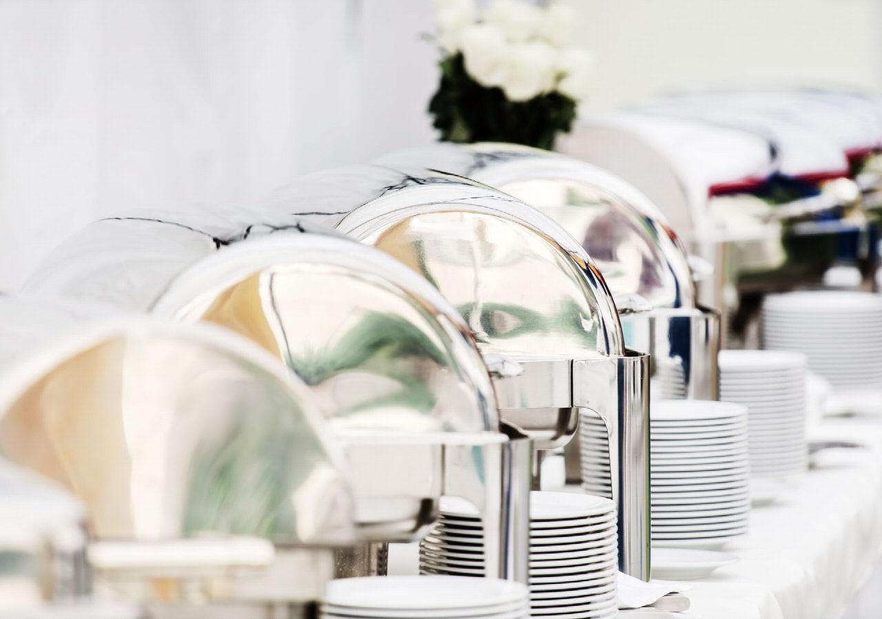 Elegantes Buffet mit Chafing-Dishes auf weißer Tischdecke